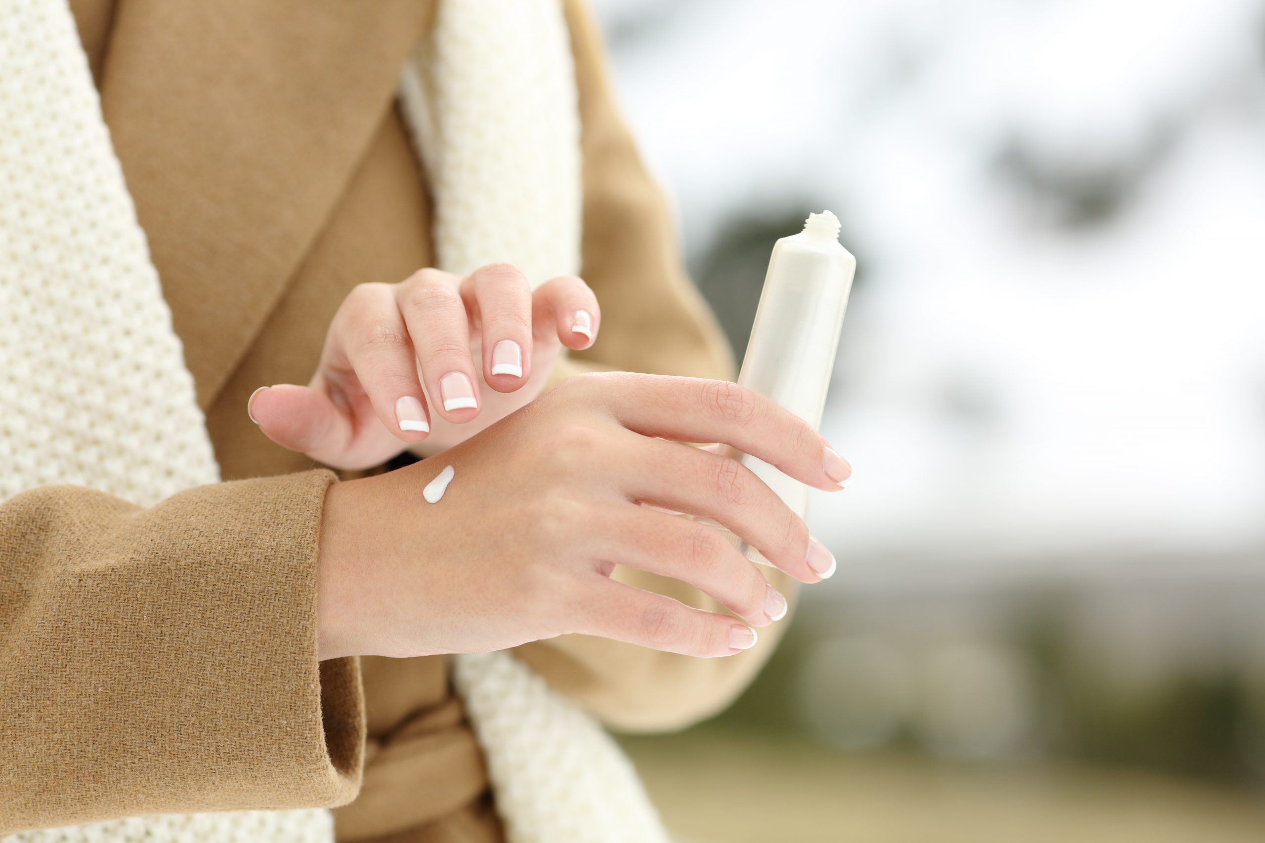Woman putting on hand lotion in winter weather